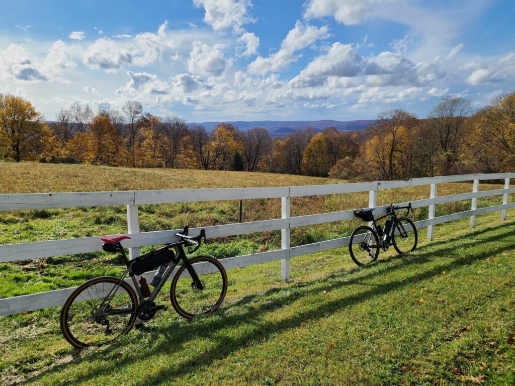 Two bikes leaning against a white fence